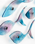 A close up of a fused glass shoal of fish in soft aqua and rose pink hues, creating an ocean inspired wall art installation. 