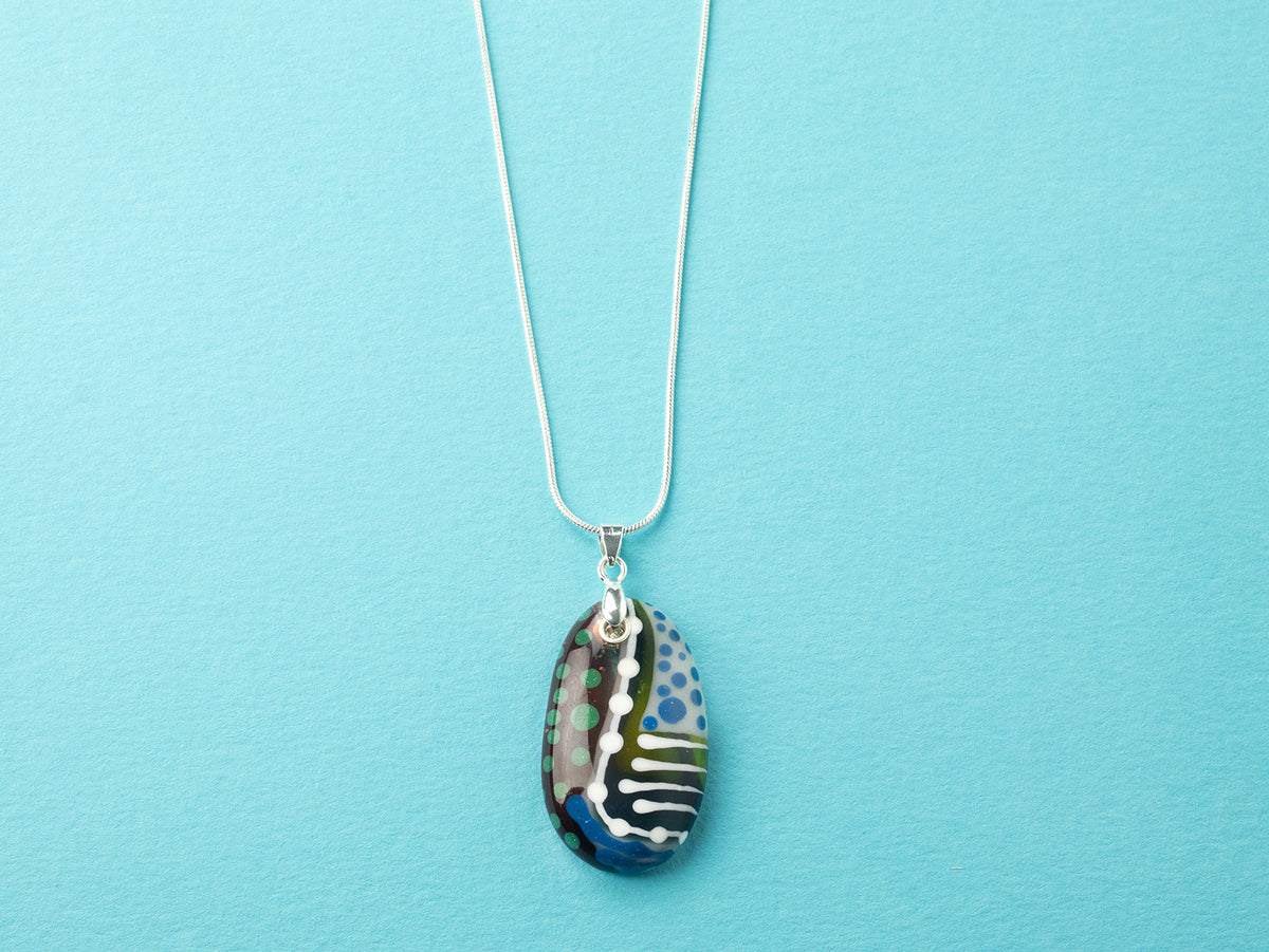 Fused glass pendant necklace handmade in rich coastal and sunset hues, including hand-painted patterns and hung on a sterling silver chain.