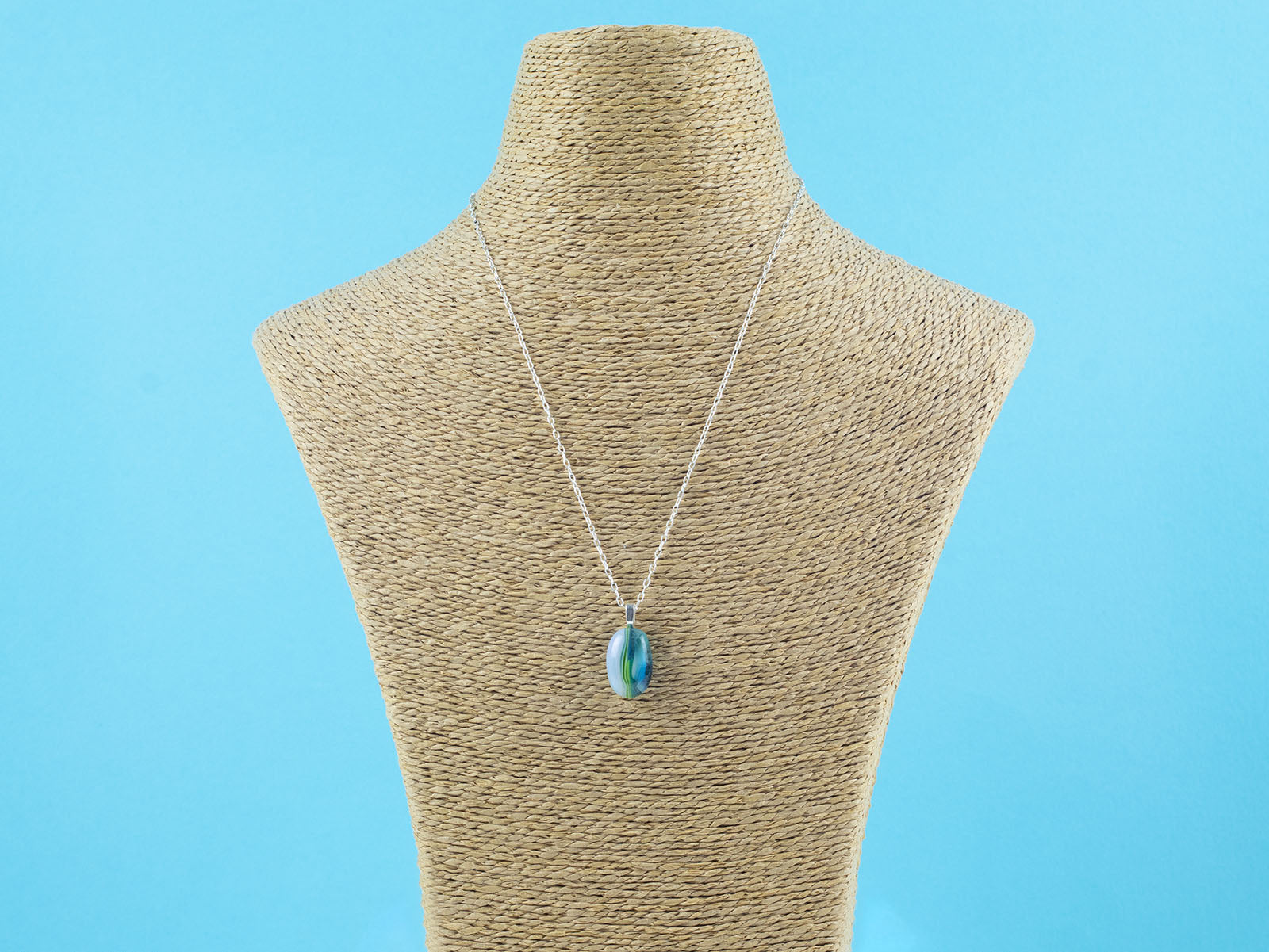 A fused glass pendant necklace on a sterling silver chain, handmade with soft coastal colours.