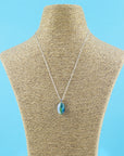 A fused glass pendant necklace on a sterling silver chain, handmade with soft coastal colours.