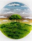 A fused glass round panel featuring a design of the "Nearly Home Trees" located on a hill over-looking the A30. 
