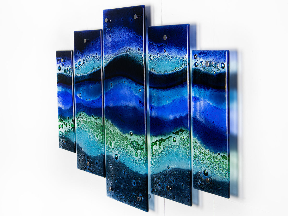 A side image of a fused glass quintych featuring an ocean blue colour-way, inspired by the coast.