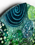 Close up of intricate hand-painted design in ocean colours, handmade in a fused glass wall panel. 