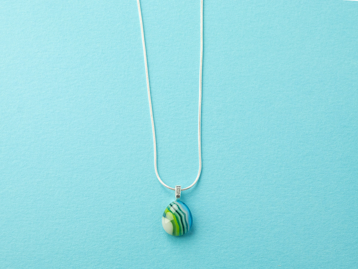 Fused glass small pendant necklace, handmade in ocean blue and green hues, hung on a sterling silver chain. 