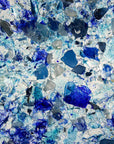 A close up of a fused glass round dish, handmade using recycled marine blue hues, designed to create a striking, ocean inspired piece of decor. 