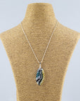 A fused glass pendant necklace on a sterling silver chain, handmade with soft coastal colours, with hand-painted dots and swirls. 