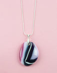 A fused glass pendant necklace hung on a sterling silver chain, handmade in heather pinks and organic deep hues. 