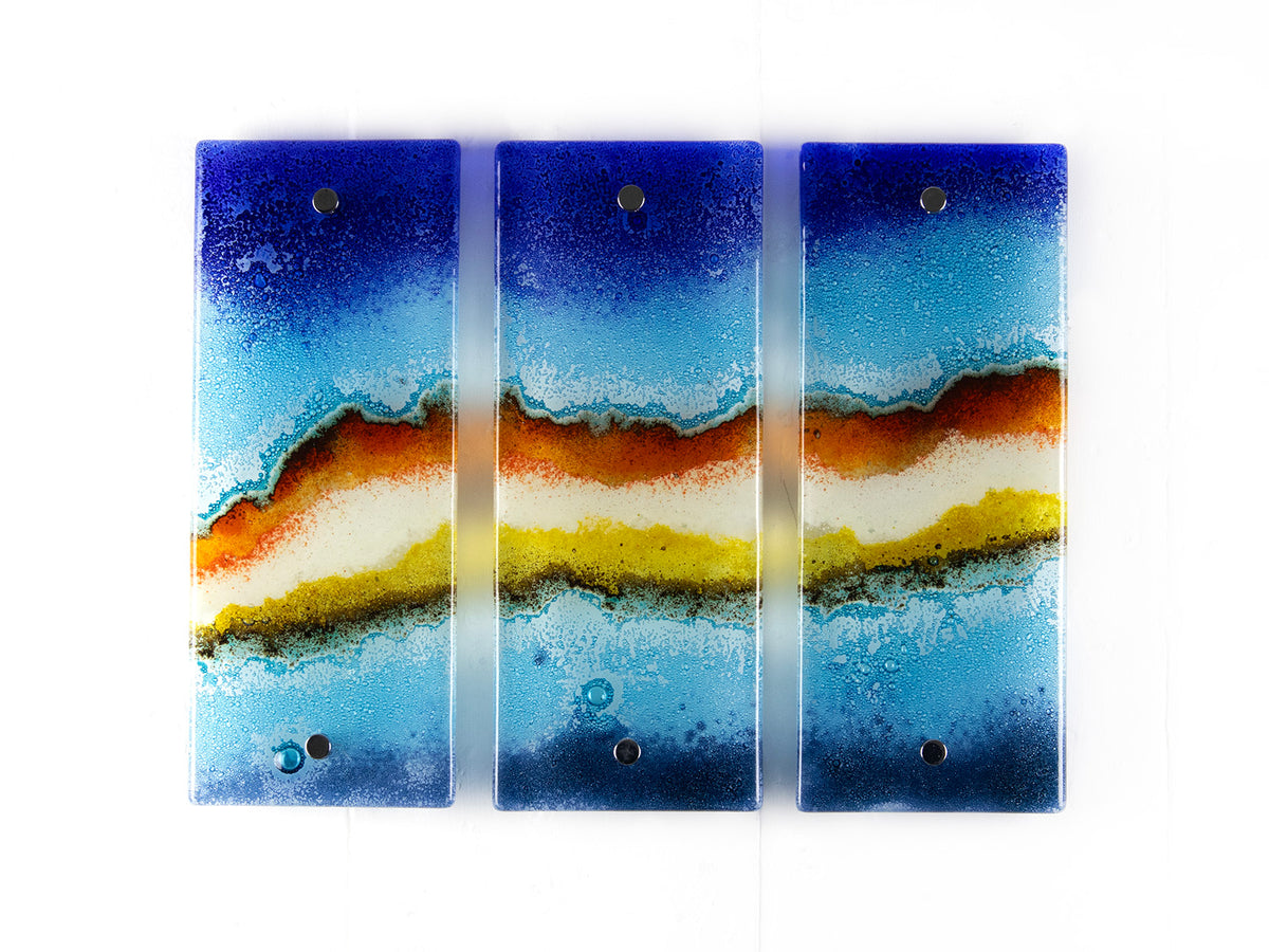 Three fused glass panels, forming a handmade triptych wall art piece, designed in coastal bright colours.