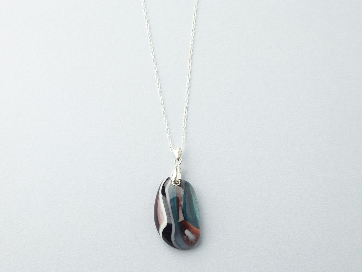 A fused glass pendant necklace, handmade in organic soft hues, hung on a sterling silver chain. 