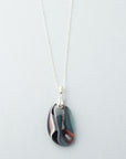 A fused glass pendant necklace, handmade in organic soft hues, hung on a sterling silver chain. 