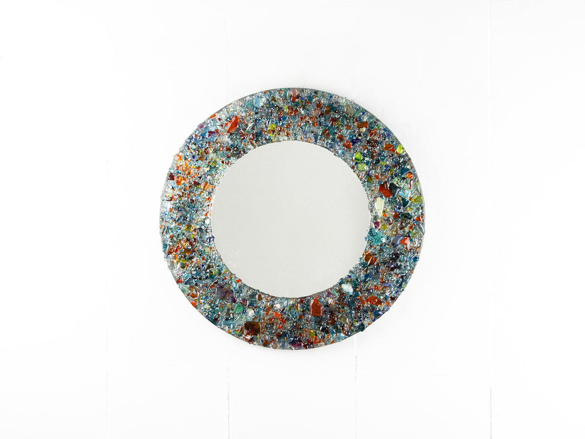 A fused glass round mirror handmade using multi coloured recycled glass, creating a striking piece of wall art. 