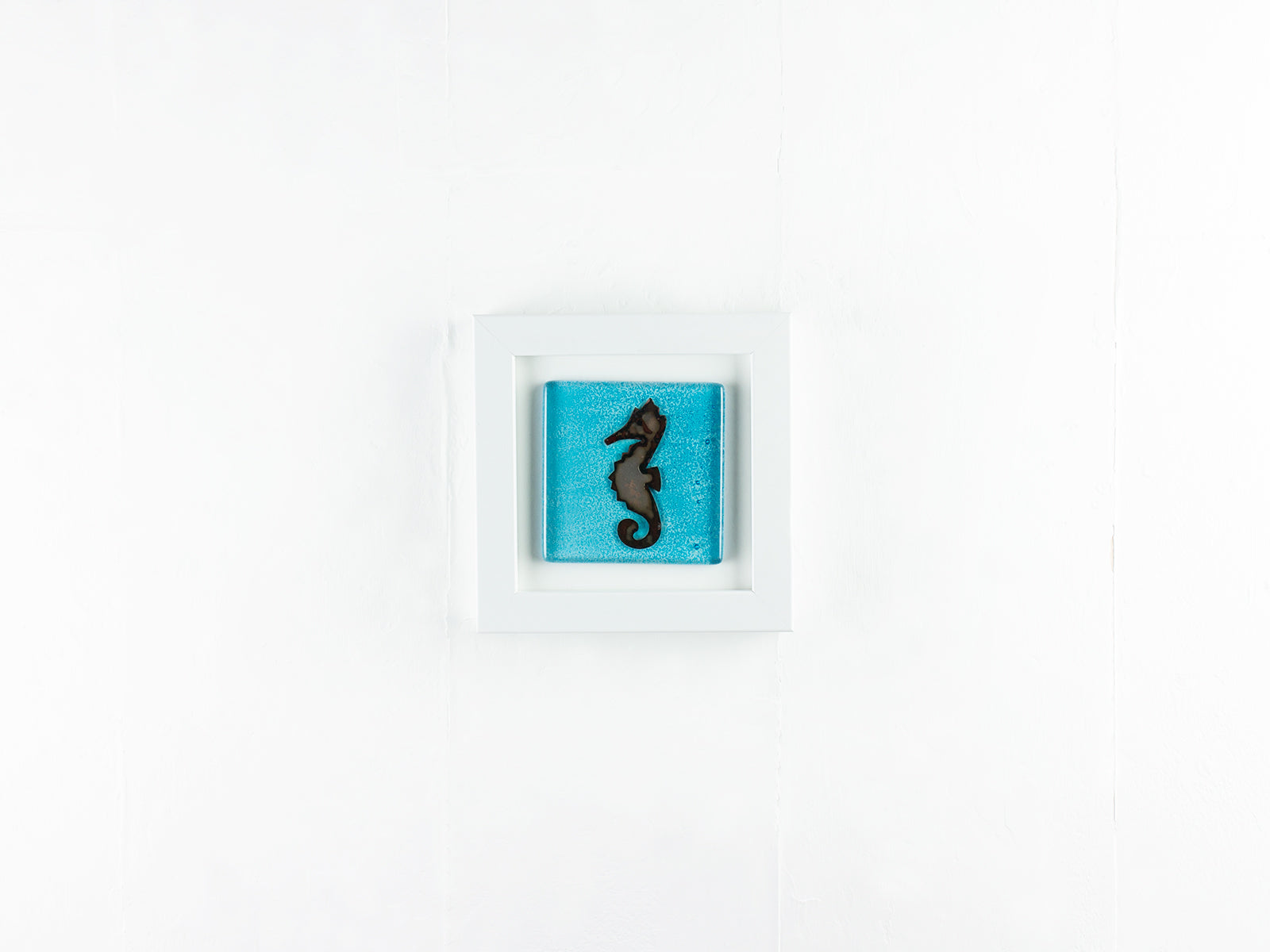 A fused glass art frame with a copper seahorse design on an aqua blue color-way, handmade.